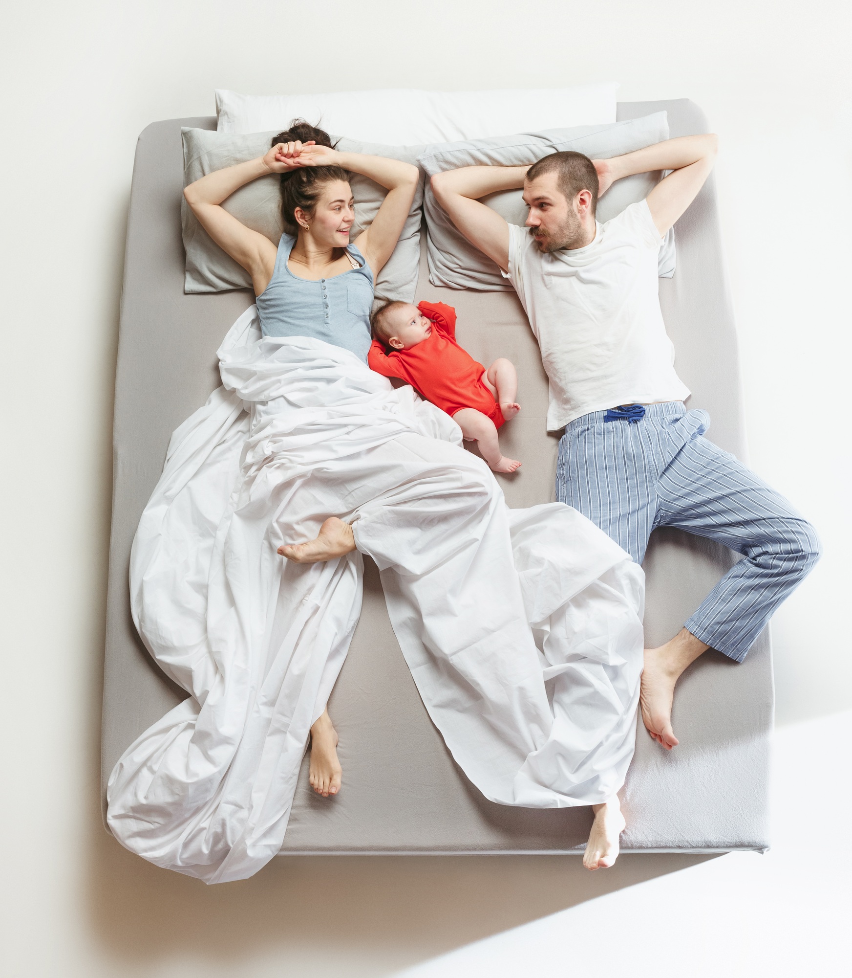 Top view of happy family with one newborn child in bedroom.